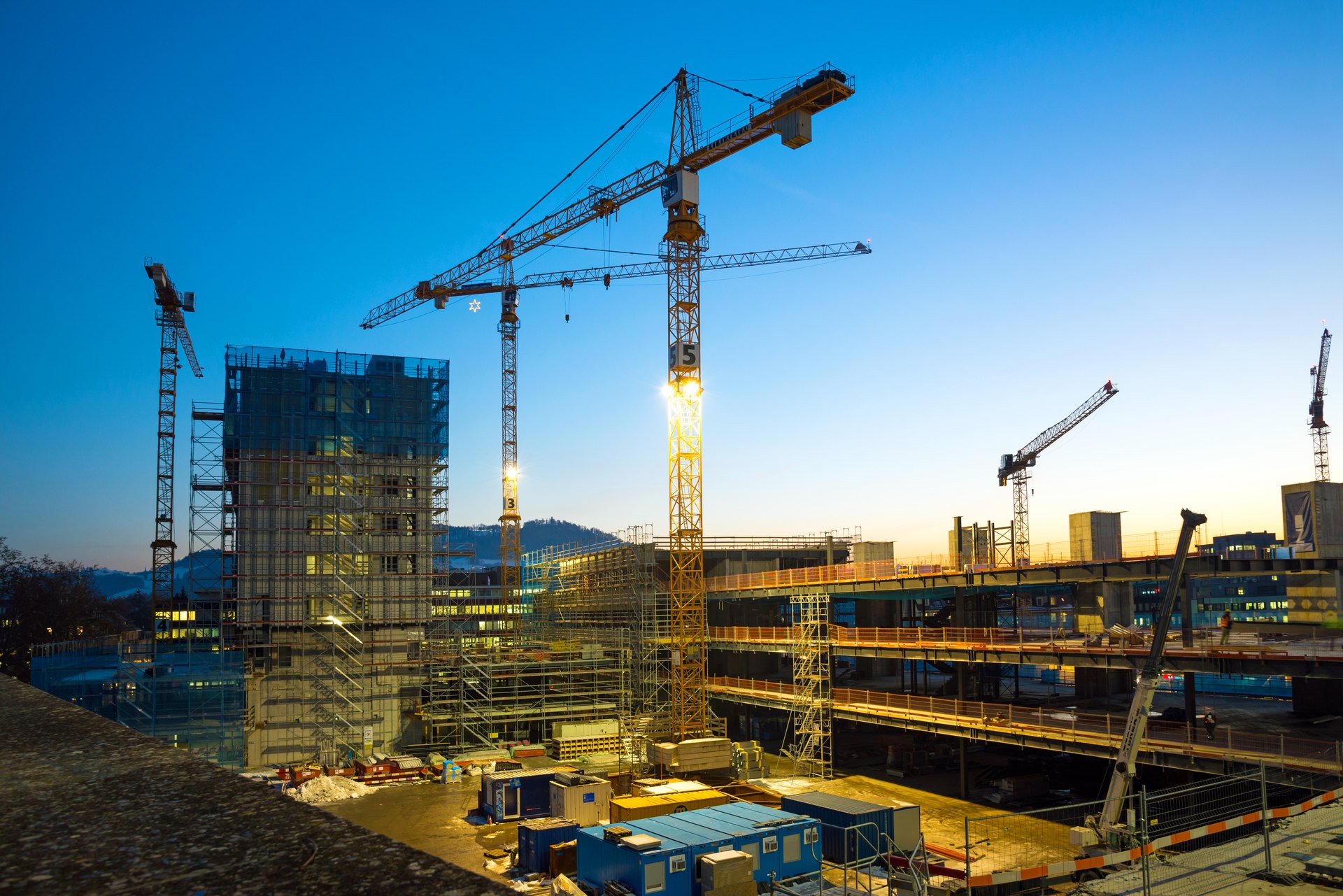 Großbaustelle mit Kränen bei Dämmerung